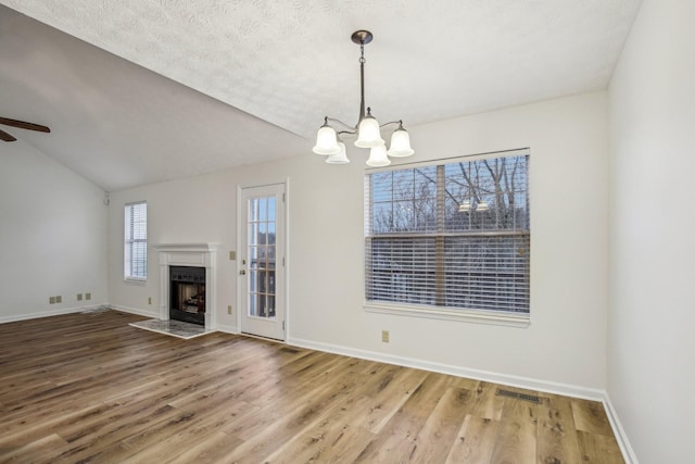 unfurnished living room featuring lofted ceiling, wood finished floors, a fireplace with flush hearth, and visible vents