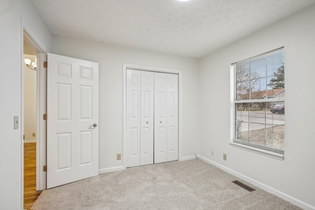 unfurnished bedroom with carpet floors, a closet, visible vents, and baseboards