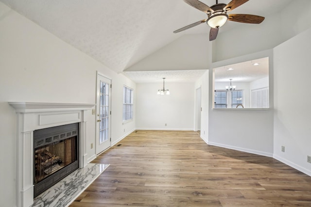 unfurnished living room featuring a fireplace with flush hearth, vaulted ceiling, baseboards, and wood finished floors