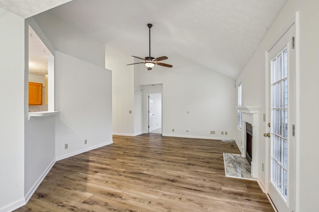 unfurnished living room with a fireplace with flush hearth, lofted ceiling, baseboards, and wood finished floors