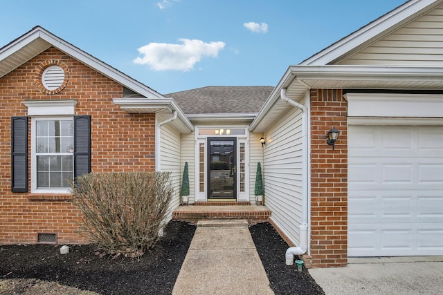 view of exterior entry with roof with shingles, brick siding, crawl space, and an attached garage