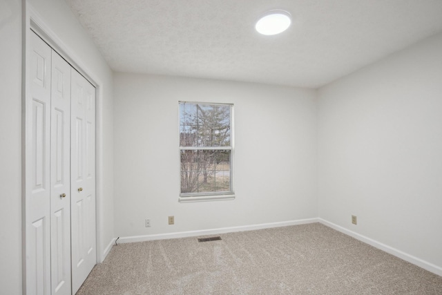 unfurnished bedroom with carpet, visible vents, baseboards, and a closet