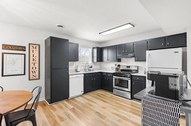 kitchen featuring light wood-style floors, a sink, stainless steel gas range, dishwasher, and under cabinet range hood