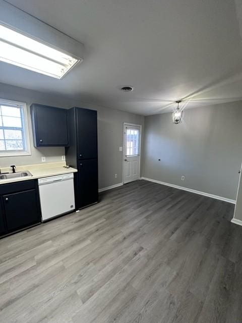 kitchen with a sink, baseboards, light countertops, light wood-type flooring, and dishwasher