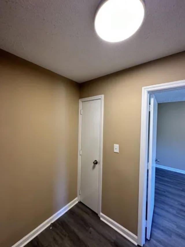 interior space with dark wood finished floors, a textured ceiling, and baseboards