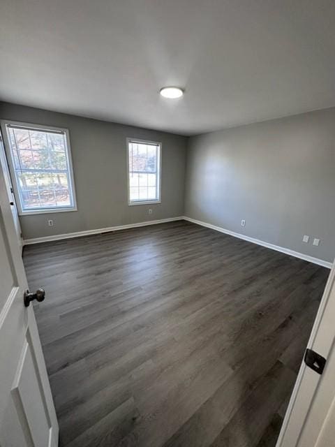 spare room featuring dark wood-style floors and baseboards