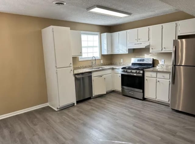 kitchen with stainless steel appliances, light countertops, visible vents, a sink, and under cabinet range hood