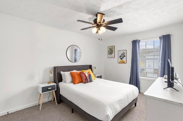 bedroom with light carpet, a ceiling fan, baseboards, and a textured ceiling