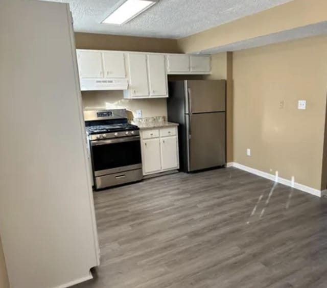 kitchen with dark wood-style flooring, appliances with stainless steel finishes, white cabinets, a textured ceiling, and under cabinet range hood