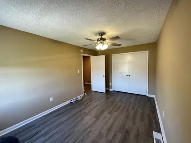 unfurnished bedroom featuring a textured ceiling, dark wood-type flooring, a ceiling fan, baseboards, and a closet