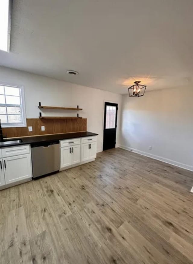 kitchen with a sink, white cabinetry, light wood-style floors, dishwasher, and dark countertops