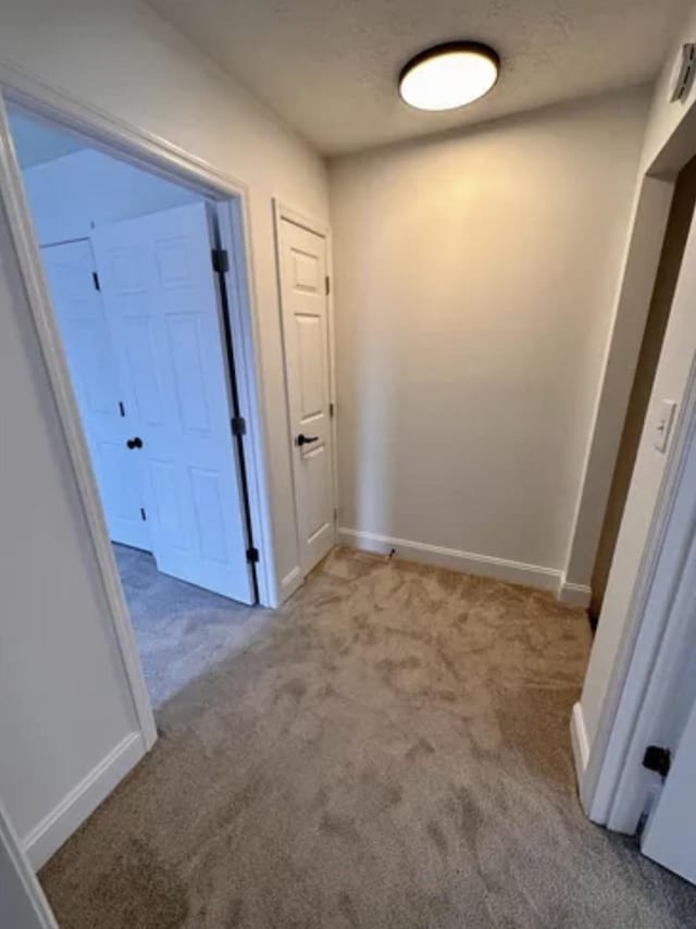 corridor with carpet flooring and baseboards