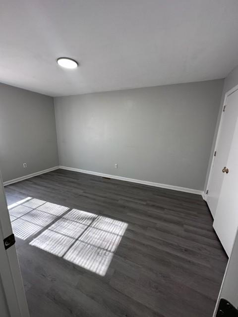 spare room with dark wood-style floors and baseboards