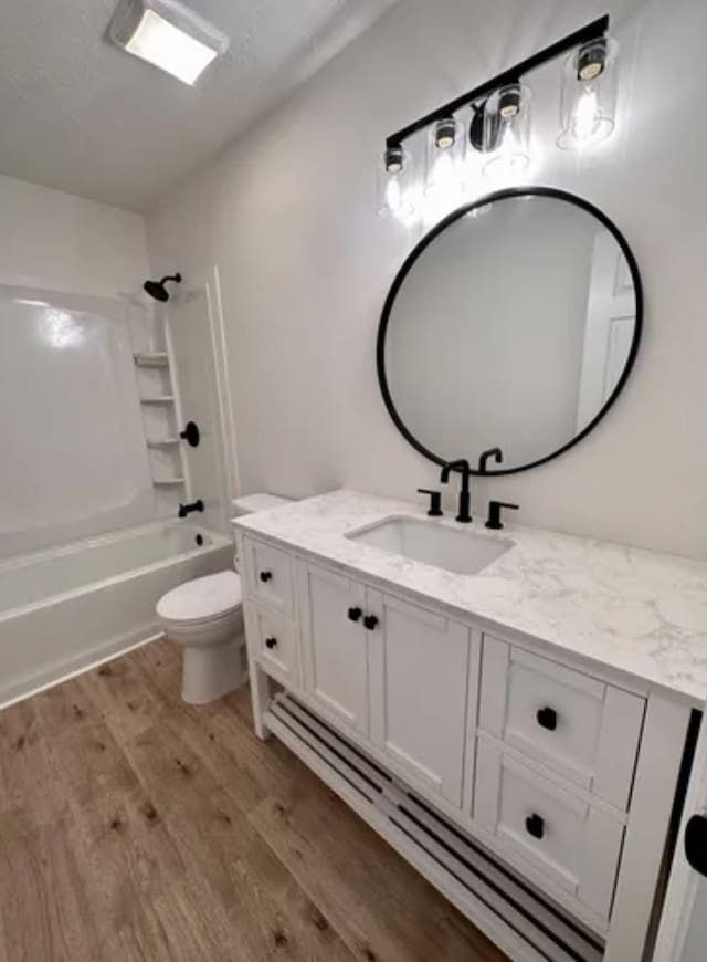 bathroom with toilet, shower / bathtub combination, wood finished floors, and vanity