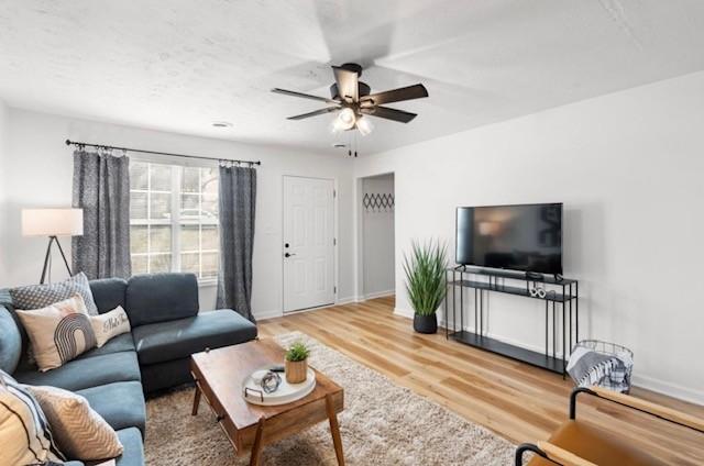 living room with ceiling fan, baseboards, and wood finished floors