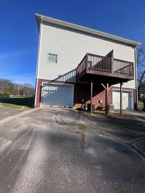 exterior space with aphalt driveway, brick siding, and an attached garage