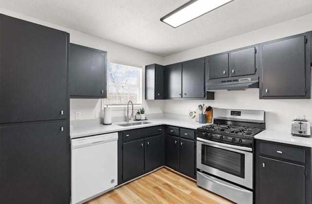 kitchen featuring stainless steel range with gas cooktop, light wood-style flooring, a sink, dishwasher, and under cabinet range hood