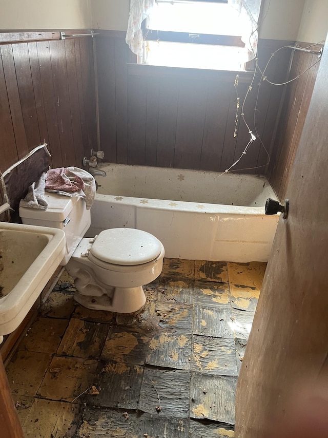 full bathroom featuring a bathtub, wood walls, and toilet