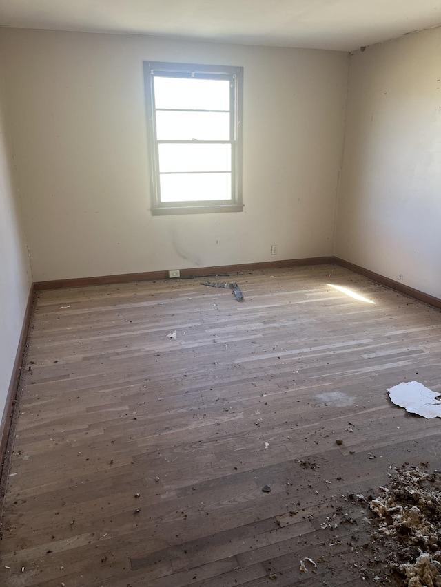 spare room with wood-type flooring and baseboards