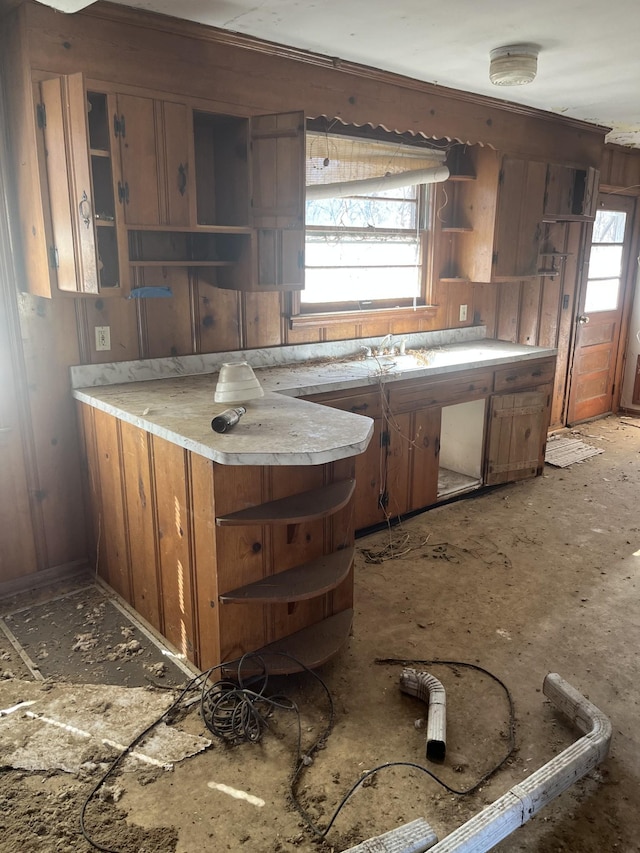 kitchen featuring a healthy amount of sunlight, brown cabinetry, open shelves, and light countertops