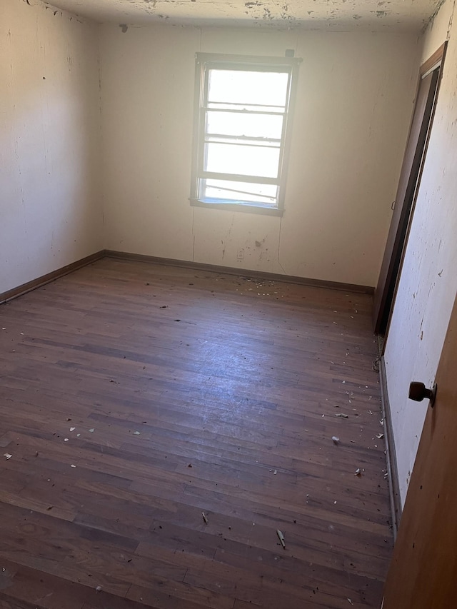 empty room with dark wood-type flooring and baseboards