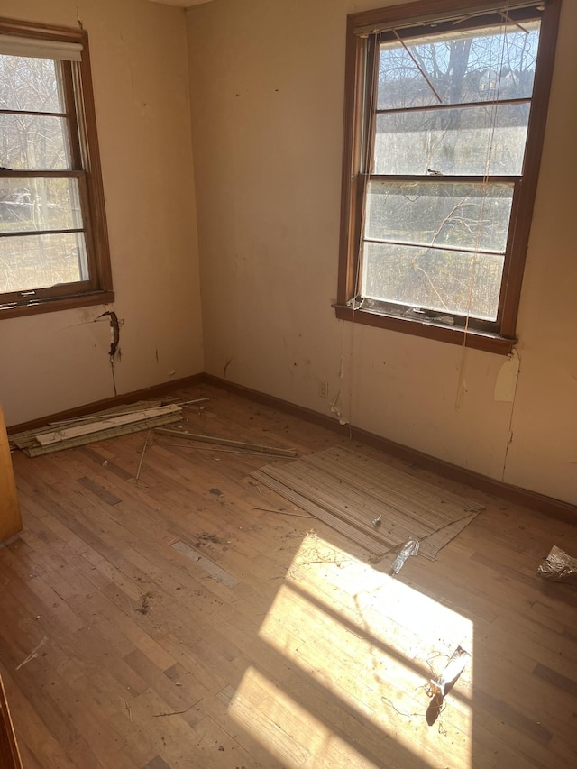 unfurnished room with hardwood / wood-style floors, plenty of natural light, and baseboards