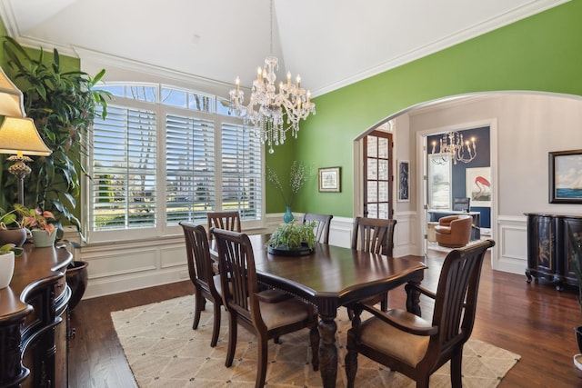 dining area with crown molding, a notable chandelier, wood finished floors, and arched walkways