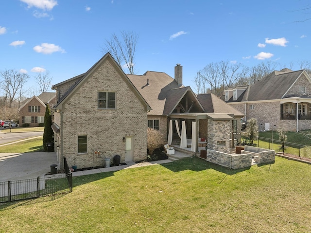 back of house featuring a yard, brick siding, a chimney, and fence