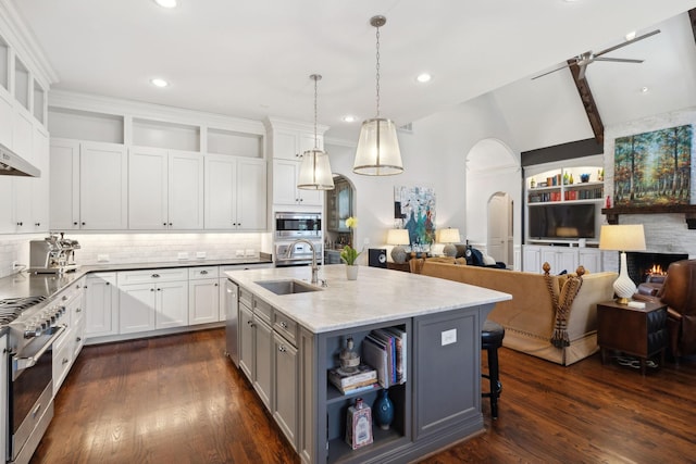 kitchen featuring stainless steel appliances, arched walkways, dark wood-style floors, and open floor plan