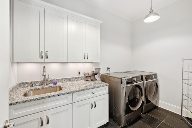 washroom with washer and clothes dryer, a sink, cabinet space, crown molding, and baseboards