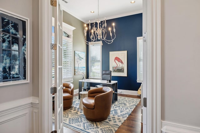 living area with an inviting chandelier, crown molding, wood finished floors, and baseboards