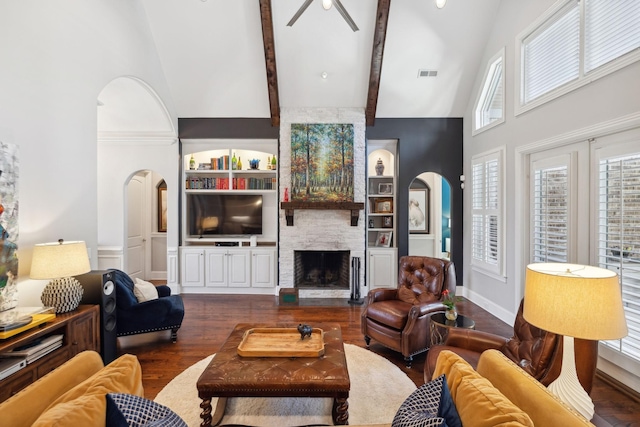 living area with visible vents, built in shelves, high vaulted ceiling, arched walkways, and a large fireplace