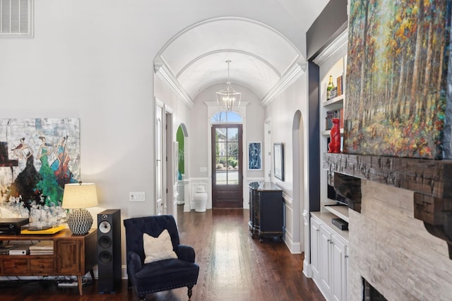 sitting room with visible vents, a fireplace, dark wood-style flooring, vaulted ceiling, and a notable chandelier