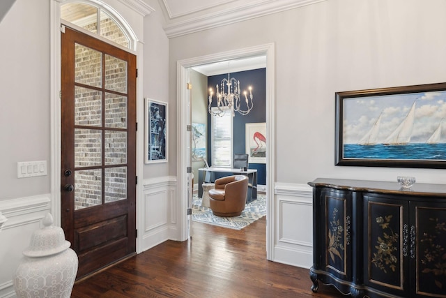 entrance foyer featuring dark wood finished floors, a chandelier, wainscoting, and ornamental molding