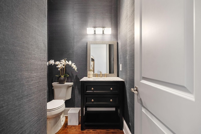 bathroom with toilet, vanity, and wood finished floors