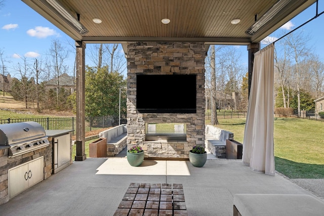 view of patio / terrace with area for grilling, an outdoor stone fireplace, an outdoor kitchen, and fence