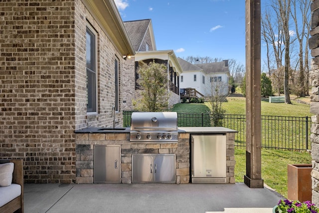 view of patio / terrace featuring fence, a grill, exterior kitchen, and a sink