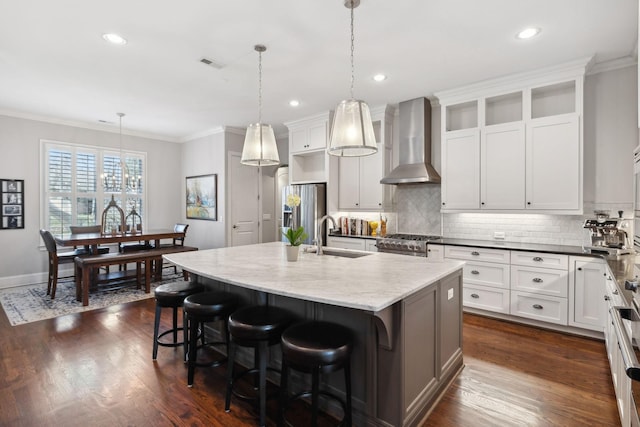 kitchen with dark wood-style floors, visible vents, ornamental molding, stainless steel appliances, and wall chimney exhaust hood