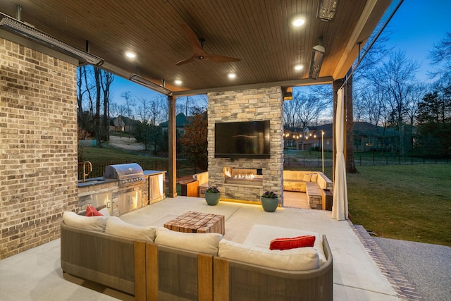 view of patio / terrace with area for grilling, an outdoor living space with a fireplace, fence, exterior kitchen, and ceiling fan