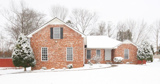 traditional-style home featuring brick siding and fence