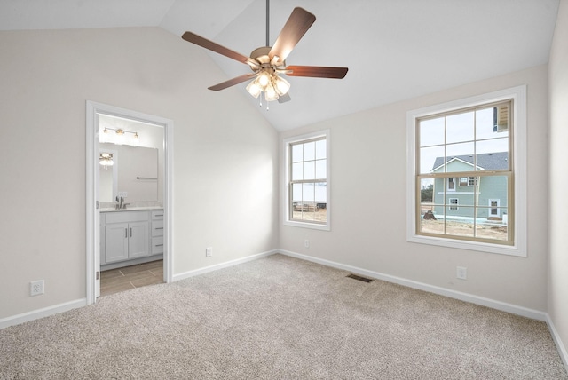 unfurnished bedroom featuring lofted ceiling, light colored carpet, a sink, visible vents, and baseboards