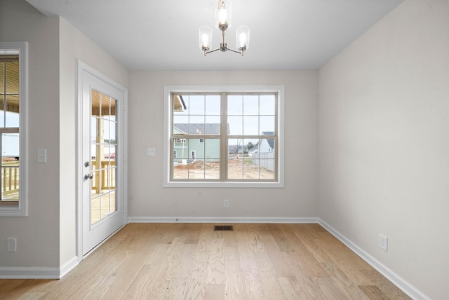 unfurnished dining area with a notable chandelier, baseboards, visible vents, and light wood-style floors