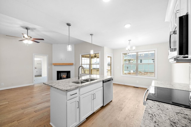 kitchen featuring a fireplace, a sink, white cabinets, appliances with stainless steel finishes, and plenty of natural light