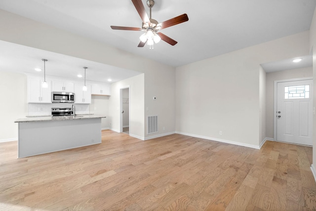 unfurnished living room featuring a ceiling fan, light wood-style flooring, visible vents, and baseboards