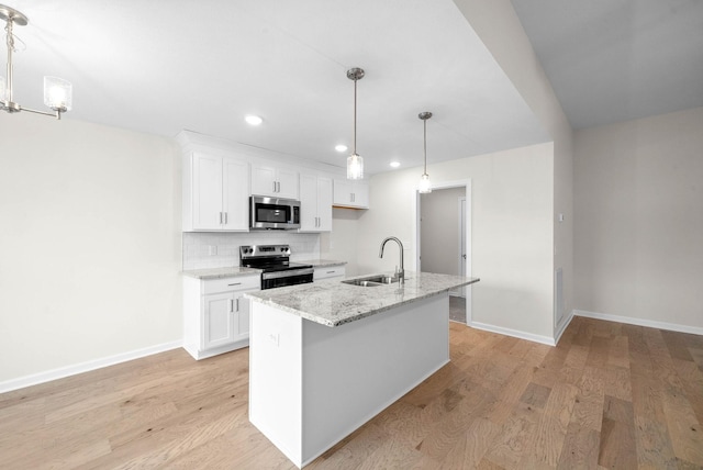 kitchen featuring decorative backsplash, white cabinets, stainless steel appliances, light wood-type flooring, and a sink