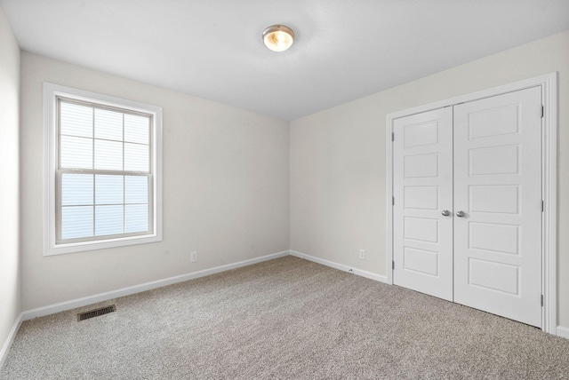 unfurnished bedroom with carpet floors, a closet, visible vents, and baseboards