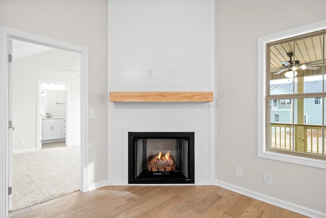 interior details featuring ceiling fan, a fireplace, baseboards, and wood finished floors