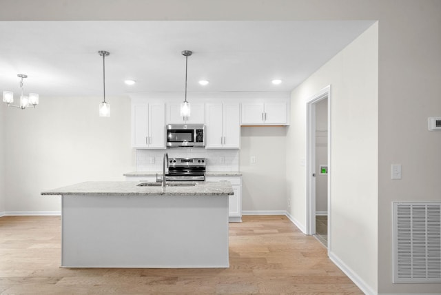 kitchen featuring stainless steel appliances, a sink, visible vents, light wood-style floors, and backsplash