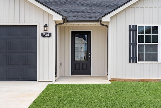 property entrance with a garage, board and batten siding, a lawn, and roof with shingles