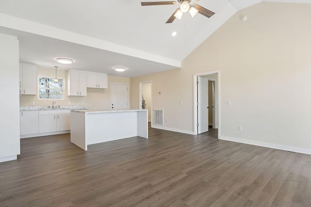 kitchen featuring visible vents, ceiling fan, a sink, white cabinetry, and a center island